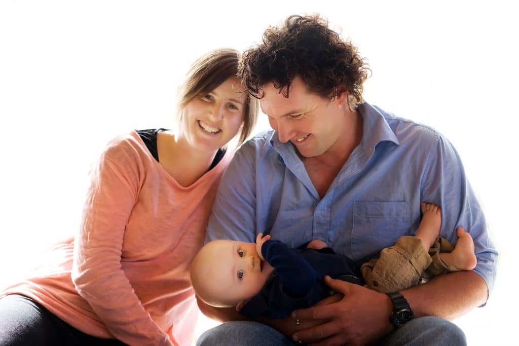 a family portrait of father holding the baby and mum looking at the camera captured by Tauranga children and family photographer Susanna